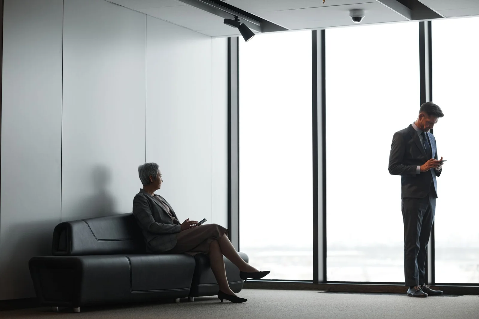 Two people waiting in a lobby by the window