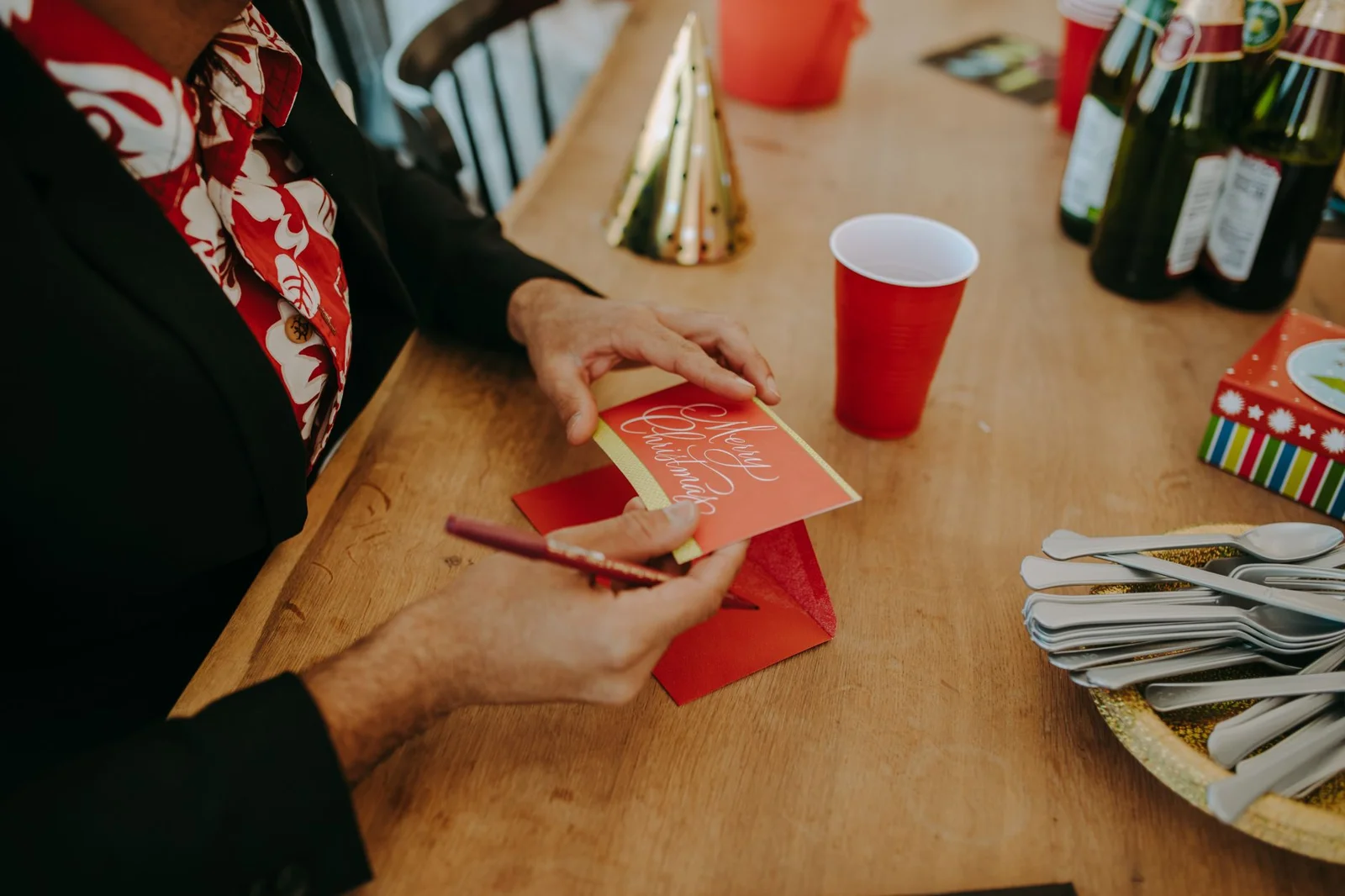 Hands signing a greeting card at a festive table